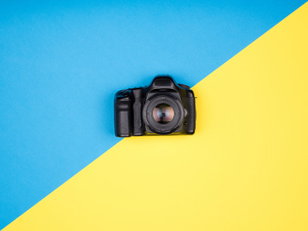 DSLR camera on blue and yellow background. Top view. Flat layの写真素材