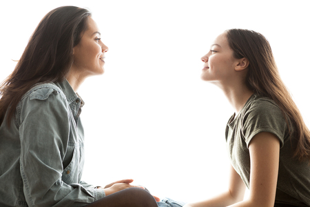 Two sisters playing with each other and having a great time together over white backgroundの写真素材