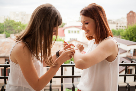 Happy female friends talking and laughing at the balcony of their appartmentの写真素材