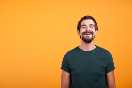 Handsome smiling man with arms at his back on orange background in studio. Portrait of happy...