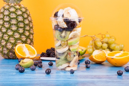 Fresh fruits on a cup with exotic fruits on wooden table. Tropical juicy healthy fruits assortement...
