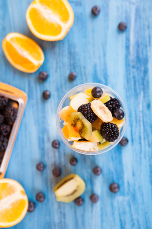 Top view of a cup full of tasty fruits in a cup . Berry, banana orange on wooden tableの写真素材