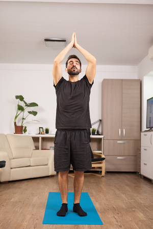 Fit man practicing yoga in the living room of his houseの写真素材