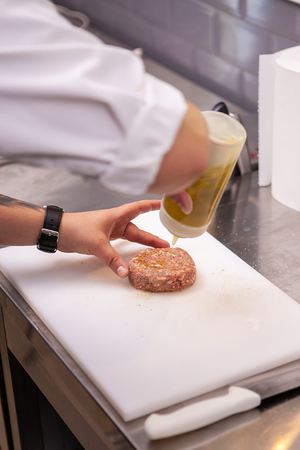 Chef seasoning burger meat in luxury restaurant kitchenの写真素材