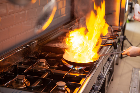 Chef cooking with flame on his restaurant kitchen.Skilled cookの写真素材