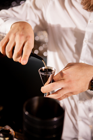 Barman adding cocktail ingredients.Barman in bar interior making alcohol cocktail.の写真素材