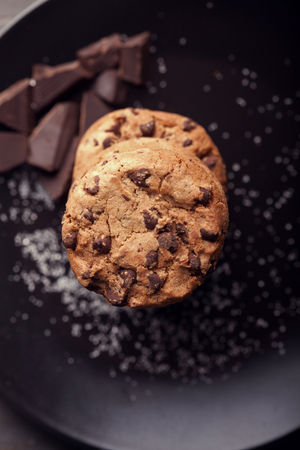 Chocolate chip cookies on black plate. Dark old wooden table.の写真素材