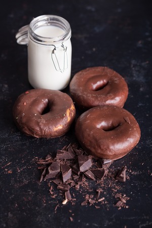 Chocolate donuts near bottle of milk and chocolate crumbs. Sweet snack.の写真素材