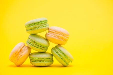 Delicate sweet french macaroons over yellow background. Sweet dessertの写真素材