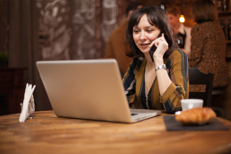 Young businesswoman talking on the while browsing on her laptopの写真素材