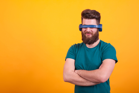 Attractive bearded man fooling around with headset over yellow background. Stylish beard. Cool man.の写真素材
