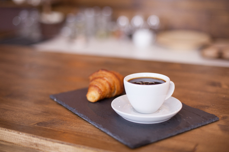 Black coffee served with pastry waiting for the client. Parisian dessert. Wooden bar counter.の写真素材