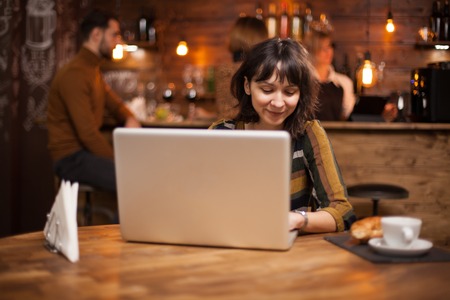 Businesswoman contemplating on great idea in front of her laptop in a coffee shopの写真素材