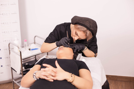 Caucasian woman removing eyebrow tattoo in her clinic