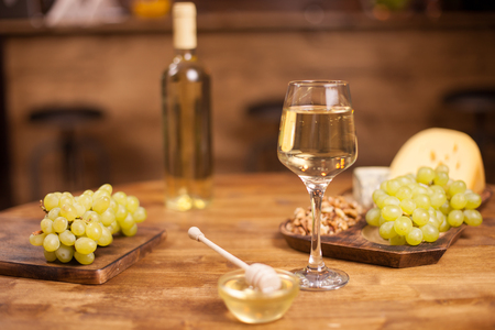 Various cheeses with a bottle and glass of wine over yellow background. Delicious fresh grapes. Tasty honey.の写真素材