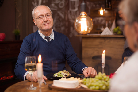 Old man looking with admiration at his old lady after all of this years of marriage. Romantic old couple. Cute old couple in a restaurant. Glass of wine.の写真素材