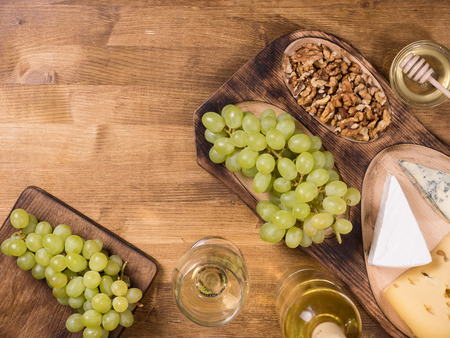 Top view of wolnuts next to fresh grapes on wooden plate in a vintage restaurant. Glas of white wine.の写真素材