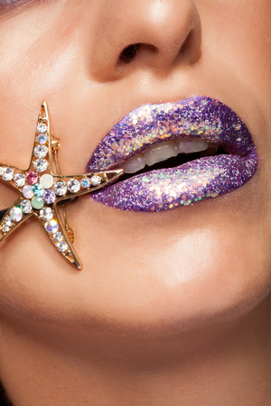 Close up of creative purple lipstick with glitter and diamond star. Studio shot. Fashion model. Lips textureの写真素材