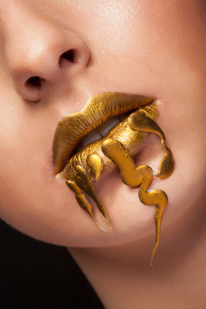 Close up golden lips of beauty model in studio. Open mouth. Shiny skin.の写真素材