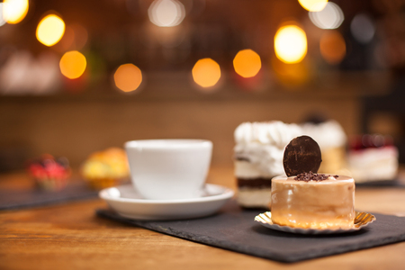 Fresh chocholate cake with sweet biscuit on top in a coffee shop. Sweet mini cakes over a wooden table in a coffee shop. Tasty desserts. Coffee shop specialities.の写真素材