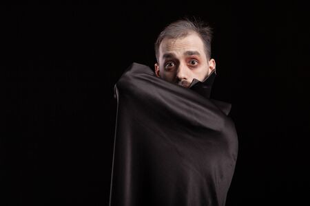 Man dressed up in dracula costume for halloween hiding behing his cape. Evil man in dracula costume....