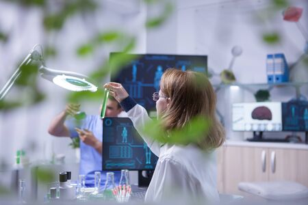 Female scientist holding and looking at a sample of liquid in a test tube. Academic scientist.の写真素材