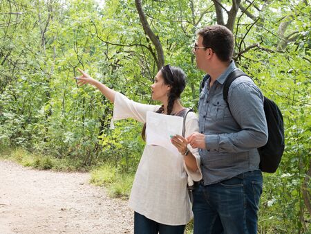 Beautiful young wife in the woods pointing on the right direction the trail. Adventure in the woods.