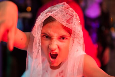 Close up portrait of screaming girl at a halloween party in weeding dress. Scary expression.の写真素材