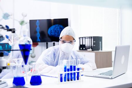 The female chemist looks at a tube holder with a blue liquidの写真素材