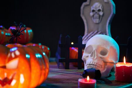 Scary skull under candle light on a wooden table for halloween celebration. Spooky pumpkin.の写真素材