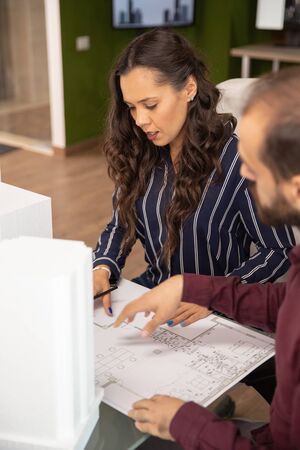 Male and female architects looking at blueprints in modern officeの写真素材
