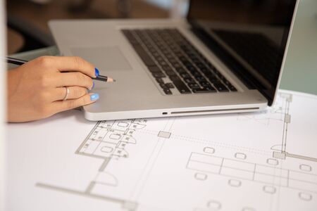 Close up shot of laptop over blueprints on the desk.