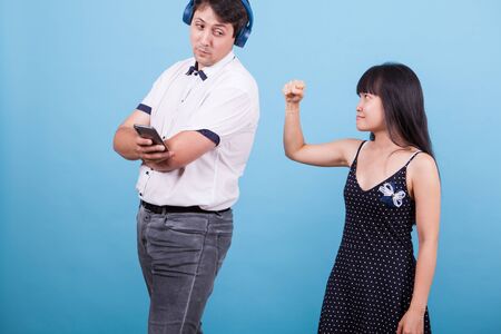 Asian girlfriend showing her fist to her caucasian boyfriend while ingnoring her. Interracial couple.の写真素材