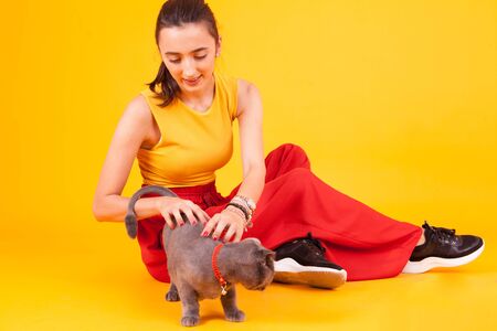 Beautiful young woman scratching the back of her adorable cat