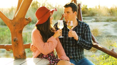 Beautiful caucasian couple in sun flares clinking glasses with white wine.の写真素材