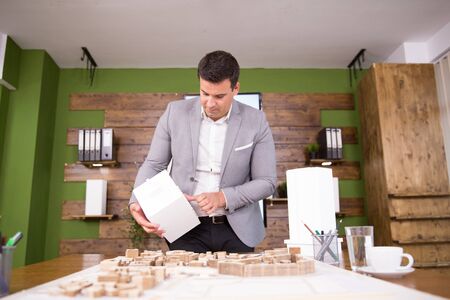 Young architect holding building model in conference room. Mini town.の写真素材
