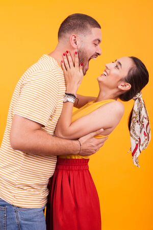 Cheerful young couple in studio over yellow background. Happy and romantic young coupleの写真素材