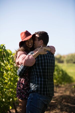 Romantic young man spinning her beautiful girlfriend in vinyard. Vinyard on the country side.の写真素材