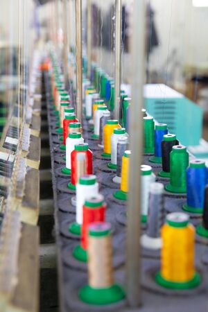 Close up with multicolored spools on an industrial sewing machine. Textile factoryの写真素材