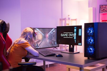 Sad girl because she lost while playing online games on computer. Girl sitting on gaming chair. Game...