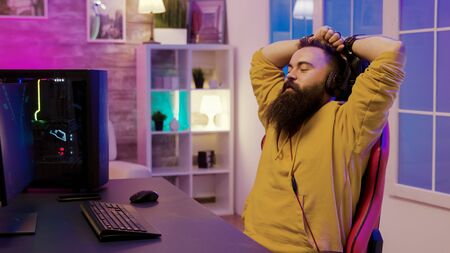 Happy bearded man after wining at online gaming. Man wearing headphones while playing video games.の写真素材