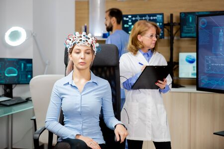 Doctor who monitors the patients evolution during the neurology headset test and notes in the clipboard. Medical experiment and studyの写真素材