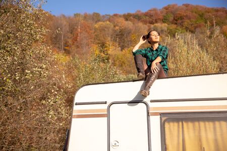 Young girl relaxing on the roof of a retro camper in a fall nightmare. Recreation vacationの写真素材