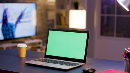 Desktop computer with green screen on home office. Businessman in the background.