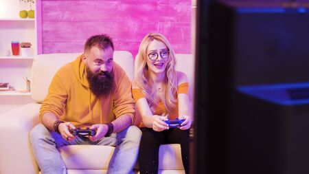 Upset young couple after losing while playing online video games using wireless controllers. Disappointment on their facesの写真素材