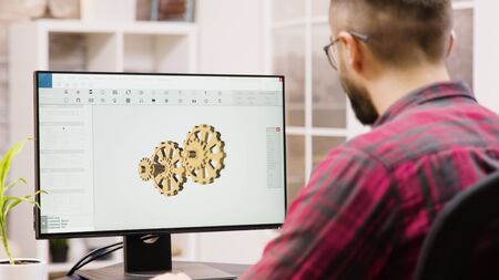 Male engineer working on a 3d design from home. Girlfriend in the background.の写真素材