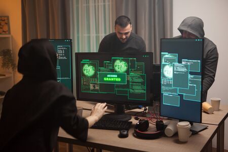 Excited female hacker after getting access granted after a cyber attack on a firewall. Team of...