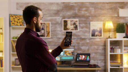 Guy uses his smart light application to turn on the light bulbs in the house. Smart future technologyの写真素材