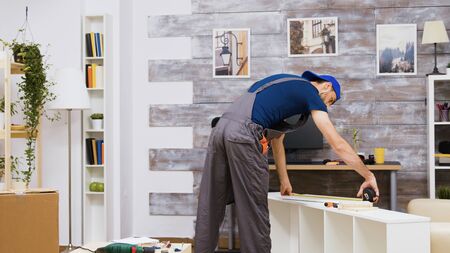 Furniture assembly worker standing reading instruction and using a tape measure. Worker tools.の写真素材