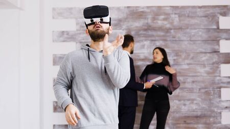 Experiencing virtual reality with headset in new apartment and woman talking with real estate agentの写真素材